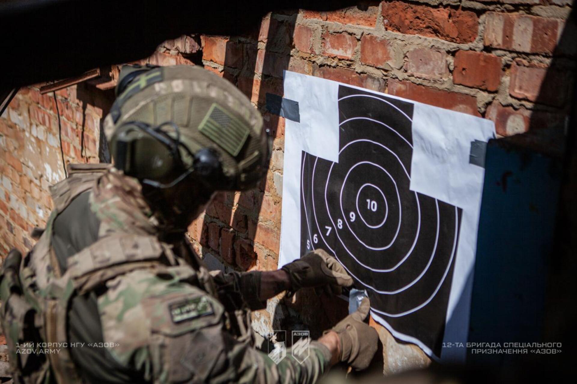 Боєць бригади «Азов» кріпить мішень для стрільб під час тренування